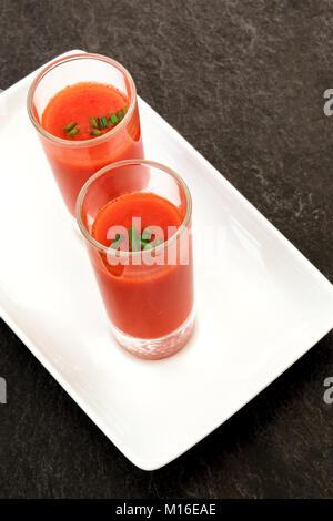 Tapas spagnole in un moderno bar. Due colpi di gazpacho, freddo minestra di pomodoro, al buio su un tavola nera con un posto per il testo Foto Stock