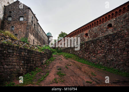 All interno della fortezza, gli edifici e le pareti sono visibili a sinistra e a destra. Viene fornito un percorso sterrato. Vyborg, Russia, dalla regione di Leningrado, storia Foto Stock