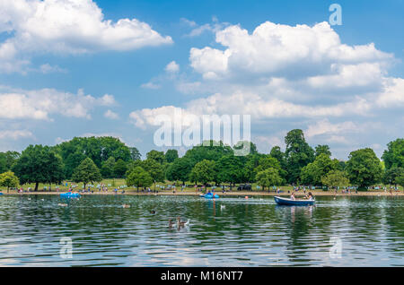 I londinesi e turisti godetevi il clima mite sulla serpentina a Hyde Park di Londra, Inghilterra Foto Stock