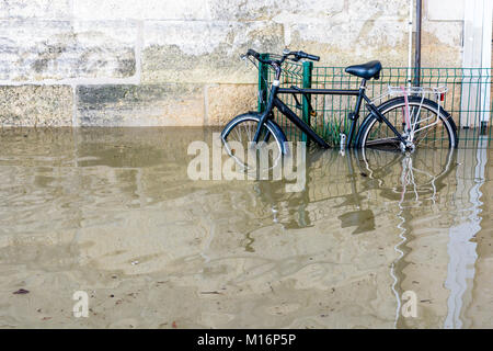 Una bicicletta fissata con un U-lock per una griglia sulle rive della Senna con acqua a metà altezza dopo il fiume gonfio scoppia le sue banche durante un w Foto Stock