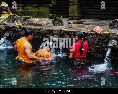 Famiglia Balinese di pregare e di balneazione a pura Tirta Empul - un indù famoso tempio di Bali Foto Stock