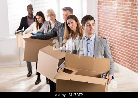 Fila di diversi imprenditori in piedi con le scatole di cartone in Office Foto Stock
