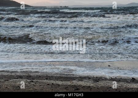 Le onde di laminazione sulla spiaggia Inverkip guardando verso la stazione di alimentazione Foto Stock
