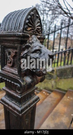 Un colpo di testa di un leone scolpito su uno dei parapetti sulle scale che conducono ai giardini di Princes Street di Edimburgo, Scozia Foto Stock