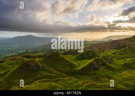 La luce del mattino si rompe attraverso le nuvole sopra l'iconica Llangattock scarpata in Usk valle al di sopra Crickhowell con lo SugarLoaf in background Foto Stock