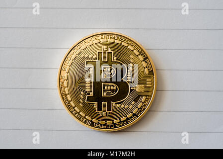 Coniate Bitcoin token cryptocurrency coin close up overhead in appoggio sul notebook bianco della carta. Foto Stock