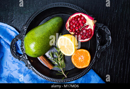 Avocado mandarino e limone su una piastra scuro Foto Stock