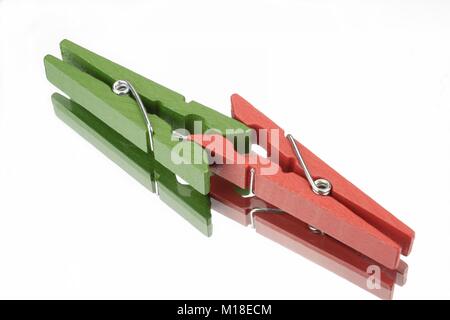 Il rosso e il verde clothespin davanti a uno sfondo bianco con riflessione speculare Foto Stock