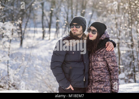 Coppia felice in posa di abiti pesanti, black hats e bicchieri Foto Stock