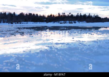 Al tramonto sul Dow del lago, Ottawa, Ontario, Canada. Un disgelo ha fuso la superficie del ghiaccio sul lago, parte del Rideau Canal Skateway, durante Winterlude. Foto Stock
