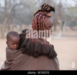 Giovani,sposato donna che indossa un bambino in un panno,ritratto,Kaokoveld,Namibia Foto Stock