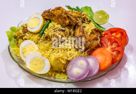 Pollo speziato biriyani riso con spicchi di uova e guarnito con verdure. Biriyani è un popolare Moghlai piatto in India. Foto Stock