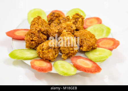 Profondo fritto di pollo croccante pakora guarnite con fettine di cetriolo e la carota. Un popolare non veg starter indiano spuntini serviti con tè o prima di principali Foto Stock