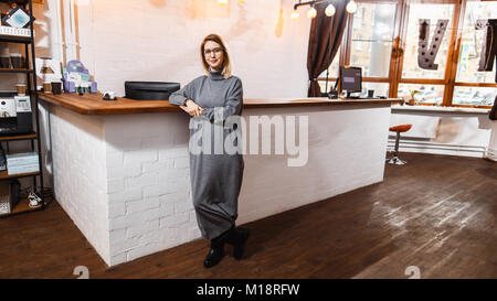 Receptionist in piedi presso il banco di ricevimento in ufficio Foto Stock