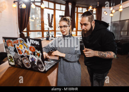 L uomo e la donna a discutere su digital portatile in ufficio creativo Foto Stock