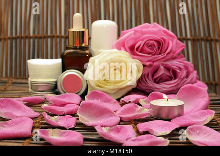 Bruciare la candela sullo sfondo di cosmetici naturali con rose e spezie Foto Stock