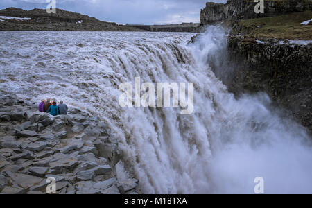 I viaggiatori Senior seduto sul bordo, contemplando Detifoss cascata. I pensionati in viaggio intorno al mondo. Foto Stock