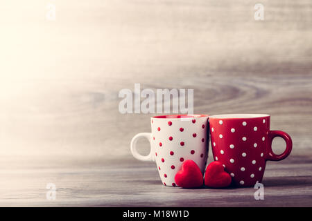 Paio di bianco e di rosso le tazze con decoro a cuori rossi su un tavolo di legno. Valentines Day celebrazione del concetto. Copia dello spazio. Foto Stock