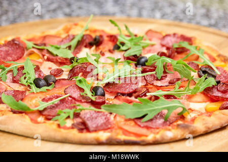 Close up salame pizza con olive nere e foglie di rucola. Foto Stock