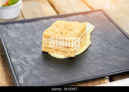 Napoleone torta sul quadrato nero piastra. Foto Stock