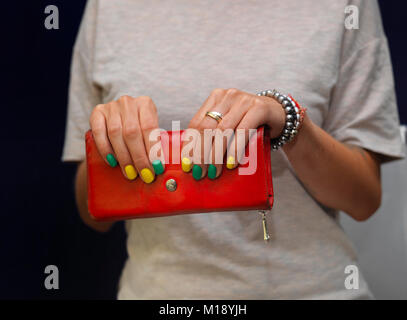 Giovane donna mani tenendo in pelle rossa borsa cosmetica, studio closeup Foto Stock
