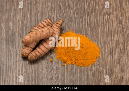 La curcuma in polvere con la curcuma root su legno Foto Stock
