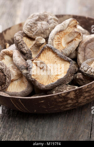 Essiccato funghi shiitake in una ciotola sul vecchio Sfondo legno close-up Foto Stock