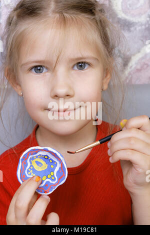 La ragazza di vernici con entusiasmo un giocattolo artigianale realizzato in argilla(focus sulla spazzola) Foto Stock