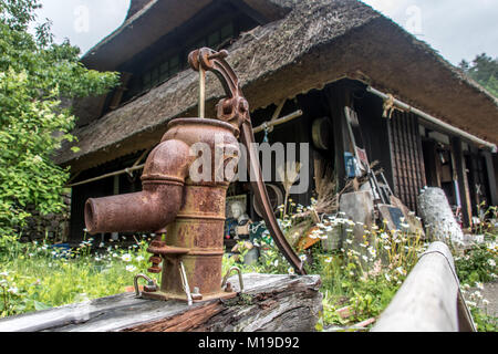 Una storica pompa acqua in un giardino nei pressi di una casa in legno sul villaggio. Il vecchio pozzo presso lo storico cottage, Giappone. Foto Stock