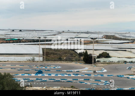 Invernaderos, serre, serre per suolo colture libero con gara di moto via in primo piano in Murcia, Spagna Foto Stock