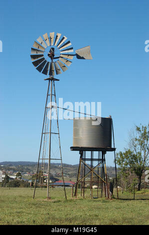 Il mulino a vento e tankstand nel paddock, Queensland, Australia. Mulini a vento sono comunemente utilizzate per il pompaggio di acqua da fori o dighe di abbeveratoi per il bestiame. Foto Stock