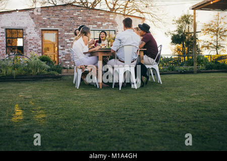 Un gruppo di giovani godendo di pasto estivo all'aperto. Millennial a pranzo insieme in un ristorante all'aperto. Foto Stock
