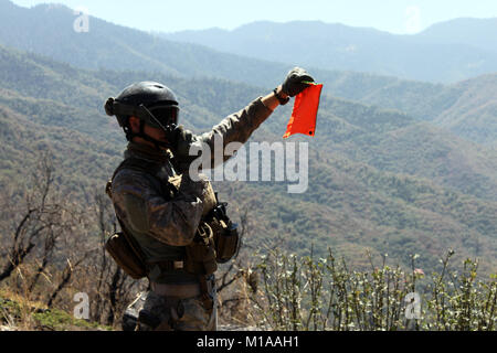 Un membro della protezione nazionale della California Counterdrug Task Force operazione di supporto Tule sul Tule River Indian Reservation segnali per un HH-60 Pave Hawk elicottero volando a tirate fuori i sacchetti di rifiuti trovati in un vecchio campeggio utilizzato dal traffico illecito di marijuana ai coltivatori. Nel corso dei quattro giorni di missione, un multi-agenzia team rimosso 12.000 libbre di cestino e 10 miglia illegale di linee di irrigazione da terre tribali. (U.S. Esercito nazionale Guard photo/ Spc. Brianne M. Roudebush/ rilasciato) Foto Stock