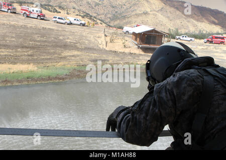 Il personale Sgt. Ge Xiong, capo equipaggio a bordo di una UH-60 Black Hawk dal teatro 1106th Aviation supporto gruppo di Manutenzione (TASMG), California Army National Guard, orologi un 2,600-gallone Bambi Bucket immergere in acqua come gli equipaggi dal dipartimento della silvicoltura e protezione antincendio (CAL FIRE) stand by durante la garza Fire in Kings County, California, 13 luglio. La garza il fuoco era uno dei circa due dozzine di incendi sfiammatura il Golden State a metà luglio 2017 secondo la CAL del fuoco sito informazioni. (Esercito Guardia Nazionale foto/Staff Sgt. Eddie Siguenza.) Foto Stock