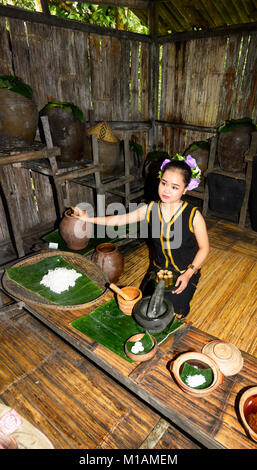 Piuttosto giovane donna che offre cibo tradizionale dei campioni a Mari Mari Villaggio Culturale, Kota Kinabalu, Sabah Borneo, Malaysia Foto Stock