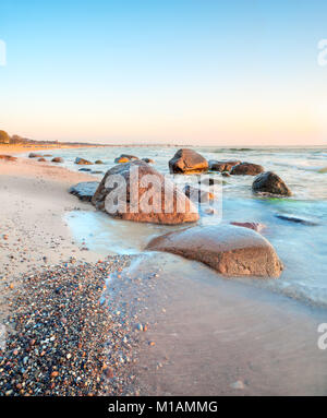 Tramonto sul Mar Baltico sulla isola di Rügen, Germania. Si tratta di tilt-shift frame, focus è sulle pietre attraverso il frame intero. Una lunga esposizione per mostrare mov Foto Stock