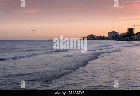 Piano di atterraggio in Larnaca. Bella serata il tramonto sul mare e dello skyline della citta'. Foto Stock