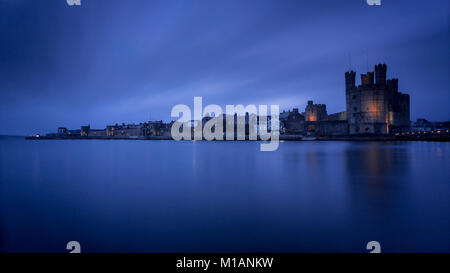 Caernarfon Castle e pareti a crepuscolo sulla costa settentrionale del Galles Foto Stock