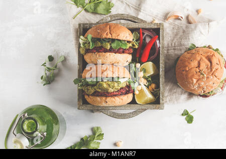 Vegan barbabietole hamburger di ceci con verdure, guacamole e ciambelle di segale in cassetta di legno. Sano cibo vegan concetto. Foto Stock