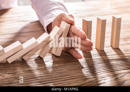 Close-up di un Business donna arresto mano blocchi che cadono sul tavolo di legno Foto Stock