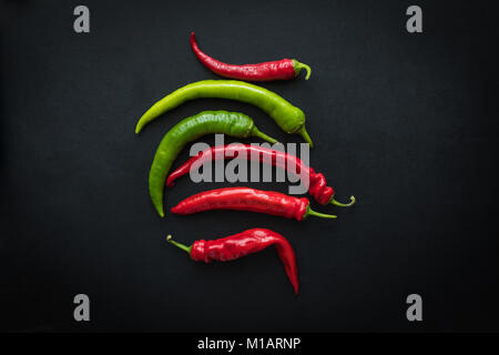 Vista superiore del rosso e del verde peperoncino fresco peperoni isolato su nero Foto Stock