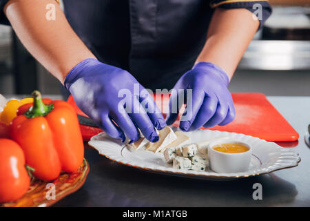 Ritagliato colpo di chef mettendo le fette di formaggio sulla piastra al ristorante Foto Stock