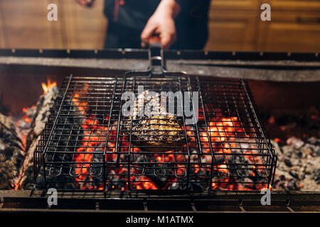 Ritagliato colpo di chef bistecca grill sulla fiamma Foto Stock