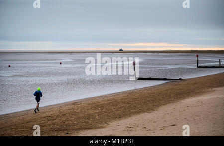 Un uomo fa avanzare in mattina presto luce sulla spiaggia di Cleethorpes nel nord-est della contea del Lincolnshire. Foto Stock