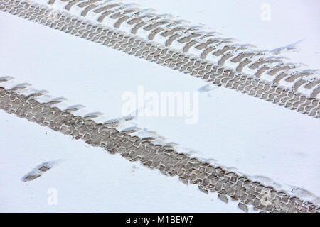 Tracce del trattore sulla coperta di neve su strada. Vista da sopra. Foto Stock