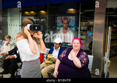 Una giovane donna sta cercando un VR (realtà virtuale) visiera, London, Regno Unito Foto Stock