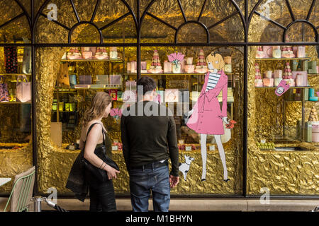 Coppia giovane cerca attraverso la finestra della sistemazione di panificio Ladurée in Burlington Archade in Londra, Regno Unito Foto Stock