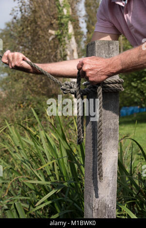 Linea di ormeggio che si terrà nelle mani dell'uomo essendo attaccato ad un posto con un giro e due attacchi per mezzo del nodo Foto Stock