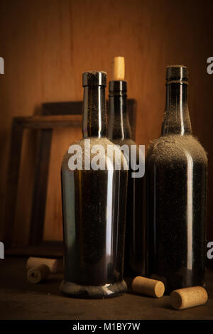 Still-life con tre vecchi vino polverose bottiglie e tappi Foto Stock