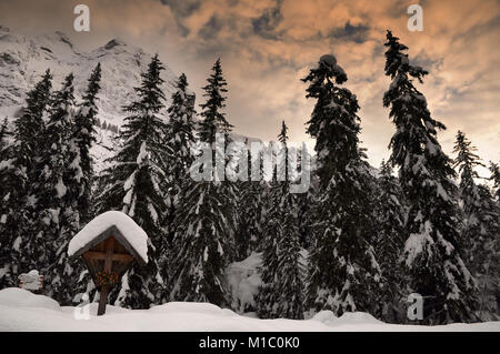 Tabernacolo in legno nella parte anteriore del innevated foresta vicino a Alba di Canazei, in Val di Fassa. Trentino Alto Adige, Italia. Foto Stock